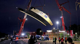 Mit riesigen Kränen, wie an einem Mobilé hängend, schwebt der Franklin-Steg Richtung Endposition. Er verbindet künftig die Stadtteile Franklin und Vogelstang.