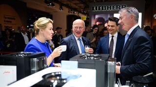 Wirtschaftssenatorin Franziska Giffey lässt sich gemeinsam mit dem Regierenden Bürgermeister Kai Wegner einen Espresso am Stand von Jura Elektrogeräte schmecken.