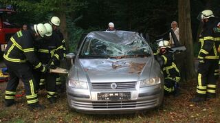 Feuerwehrmänner öffnen das verunglückte Auto. Foto jkl