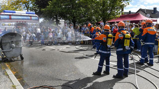 Die Jugendfeuerwehr löscht beim Tag der offenen Tür der Freiwilligen Feuerwehr Feudenheim vor zahlreichen Zuschauern einen brennenden Müllcontainer.