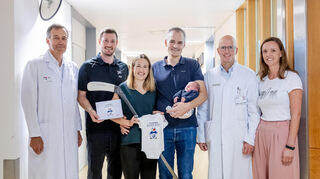 Frauenklinik-Direktor Marc Sütterlin (v.l.), Adler-Stürmer Tom Kühnhackl, Julia Keller, David Schneider mit Maila, stellvertretender Klinikdirektor Benjamin Tuschy und Diana Haase, Leitende Hebamme.