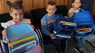 Drei Kinder freuen sich über die Erstausstattung für den Start in die Grundschule.