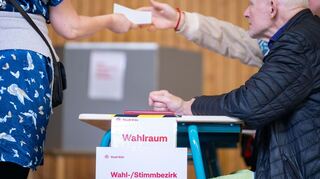 Eine Wahlhelferin gibt einen Stimmzettel aus. Landesweit fällt die Wahlbeteiligung unterschiedlich aus.