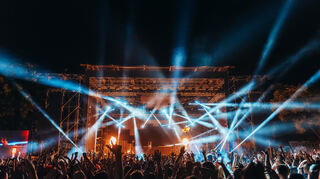 Silhouettes of concert crowd in front of bright stage lights on a music festival