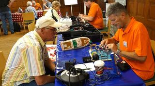 Mit Engelsgeduld tüfteln und schrauben die Technik-Experten des Repair Cafés im Gemeindesaal der Christuskirche an alten Kassenrekordern, Handstaubsaugern, Leuchten und hier Ralf Sensbach (vorne rechts) am mehr als 25 Jahre alten Spielzeugboot von Axel Fechner (links).
