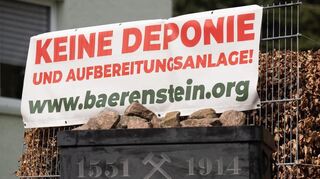 Ein Banner der Bürgerinitiative Bärenstein mit der Aufschrift „Keine Deponie und Aufbereitungsanlage“ hängt im Altenberger Ortsteil Bärenstein am Straßenrand hinter einer Güterlore.