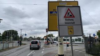 Dieses weiße Schild wurde offensichtlich abzubauen vergessen. Denn Radfahrer und Fußgänger können hier nun wieder geradeaus über die Ampel und müssen nicht mehr auf die andere Straßenseite wechseln.