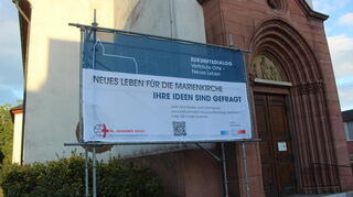Ein großes Plakat an der Marienkirche macht auf die Ideensammlung zur Zukunft von drei Viernheimer Kirchen aufmerksam.