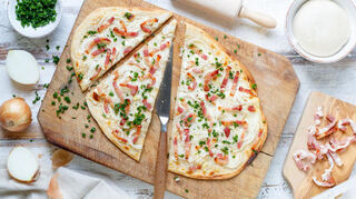 Der Teig für den Flammkuchen sollte möglichst hauchdünn ausgerollt werden. Nach dem Belegen backt er ca. 15 Minuten bei 250 Grad.