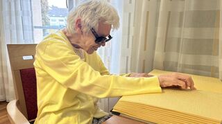 Maria Karusseit in ihrem Zimmer beim Lesen eines Buchs in Blindenschrift.