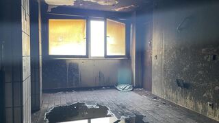 Im Hausflur des elften Stocks, auf dem das Feuer ausgebrochen ist, hat sich eine Pfütze durch das Löschwasser gebildet, die Wände sind schwarz und Fenster vergilbt.