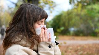 Wer niesen muss, sollte sich von anderen Personen abwenden und ein Taschentuch oder die Armbeuge vor Mund und Nase halten (Symbolbild).