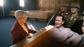 Eine Szene aus dem Dokudrama: Lauren Michel Shahar im historischen Gerichtssaal. Auf die Anklagebank haben die Filmemacher die historische Aufnahme montiert, aufwändig nachkoloriert ist darauf Hermann Göring zu sehen.