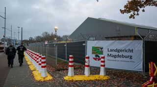 Polizisten laufen vor dem temporären Gerichtsgebäude des Landgerichtes Magdeburg Streife.