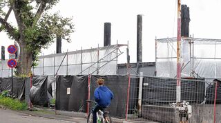 <p>Mit einem vier Meter hohen Zaun ist in der Hafenstraße die Brandruine umgeben, die Ende Juni nach dem Großfeuer in einer Lagerhalle übrig blieb.</p>